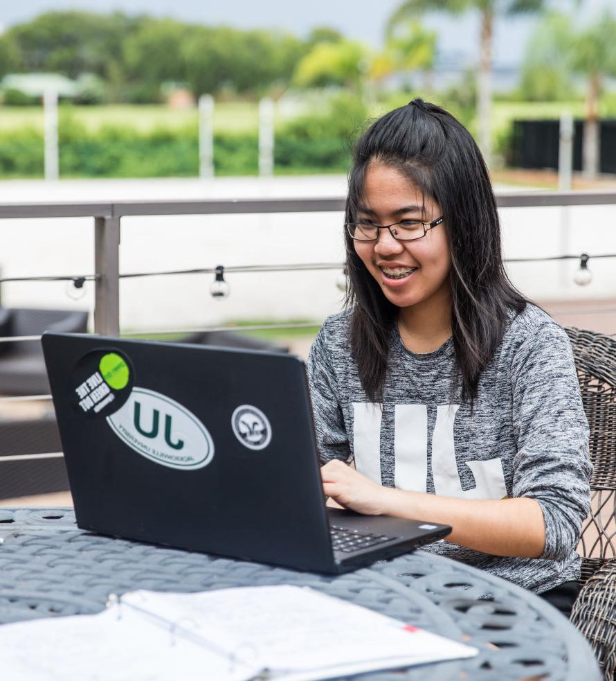 A student seating at an outdoor table with her laptop.